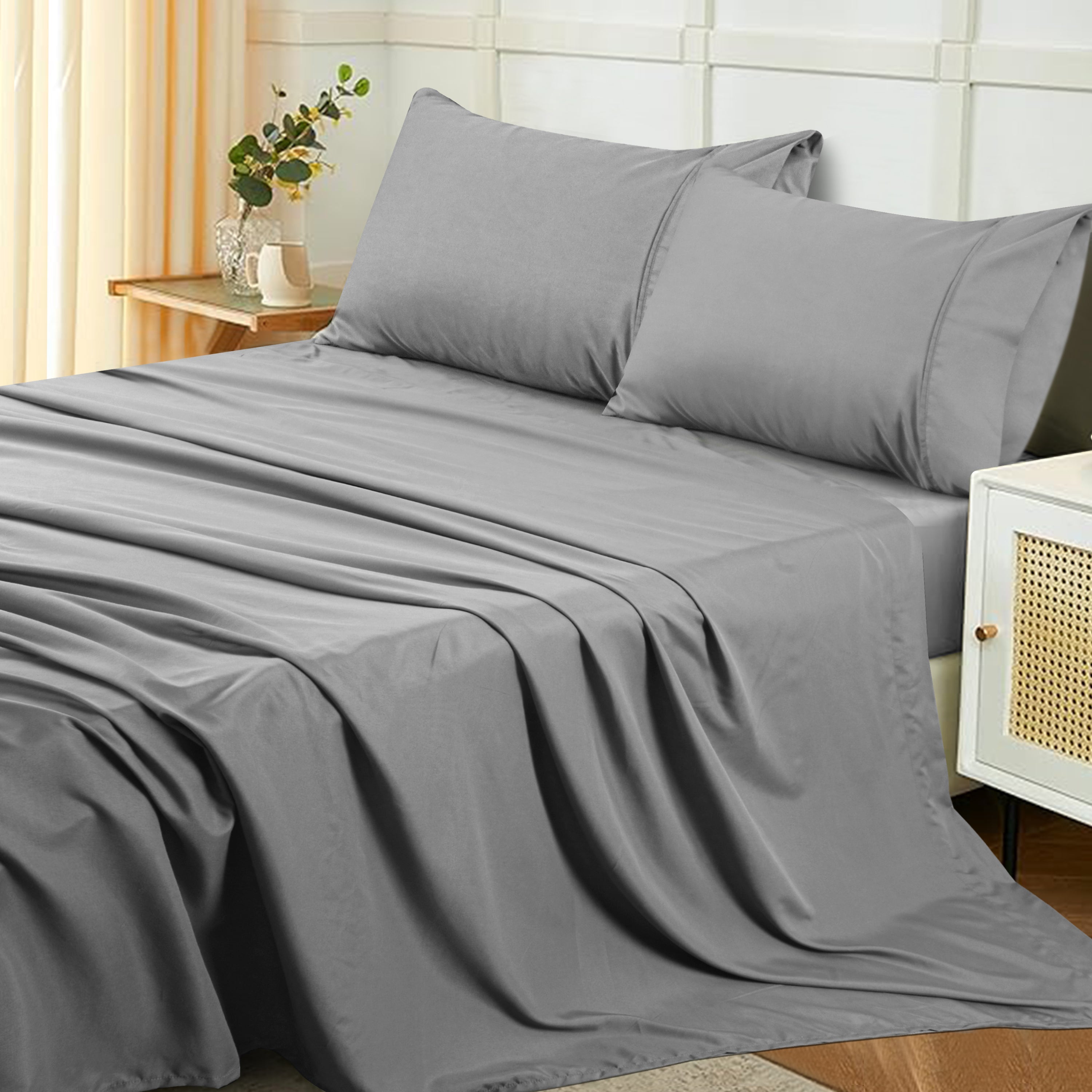 Gray bed sheets and pillows on a neatly made bed in a bedroom setting.